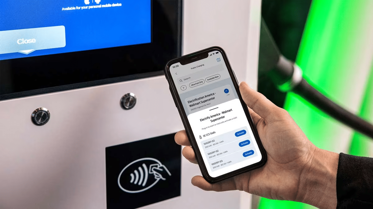 Hand holding phone in front of electric charging station