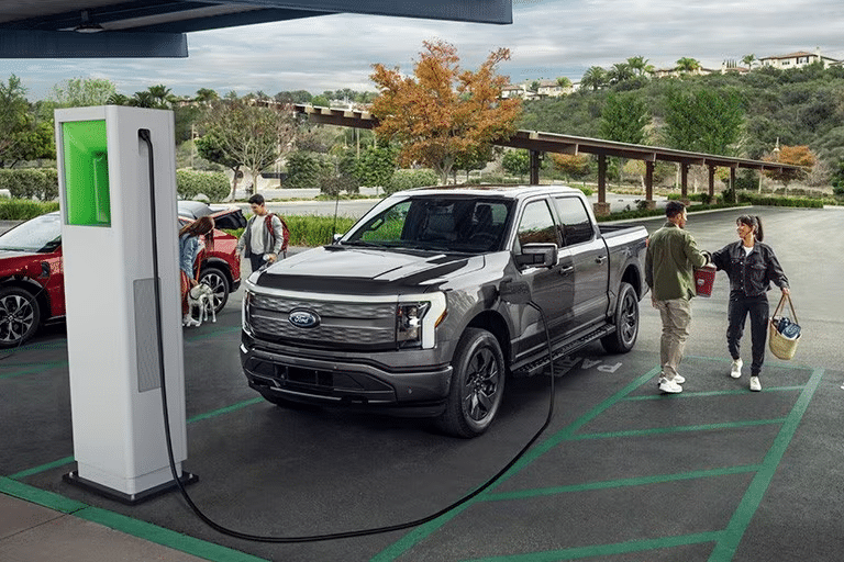 A couple stand next to a Ford F-150 Lightning parked at a D C fast charging station
