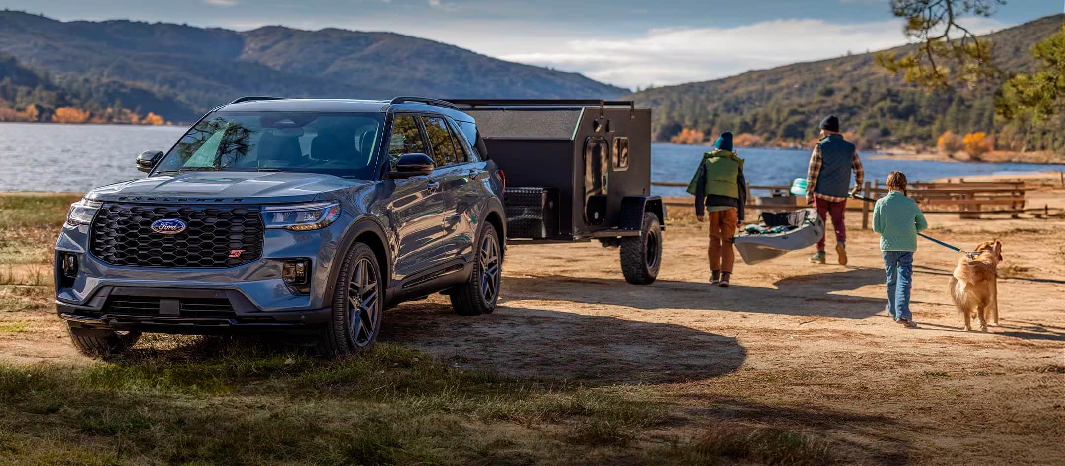 Ford Explorer with attached trailer parked by a lake.