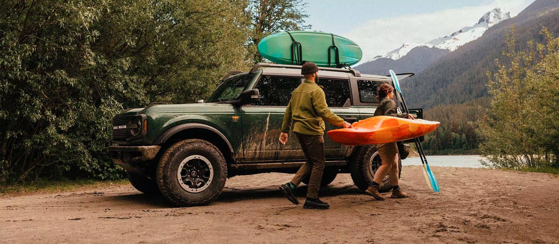 A man and woman load kayak gear onto a Ford Bronco SUV.