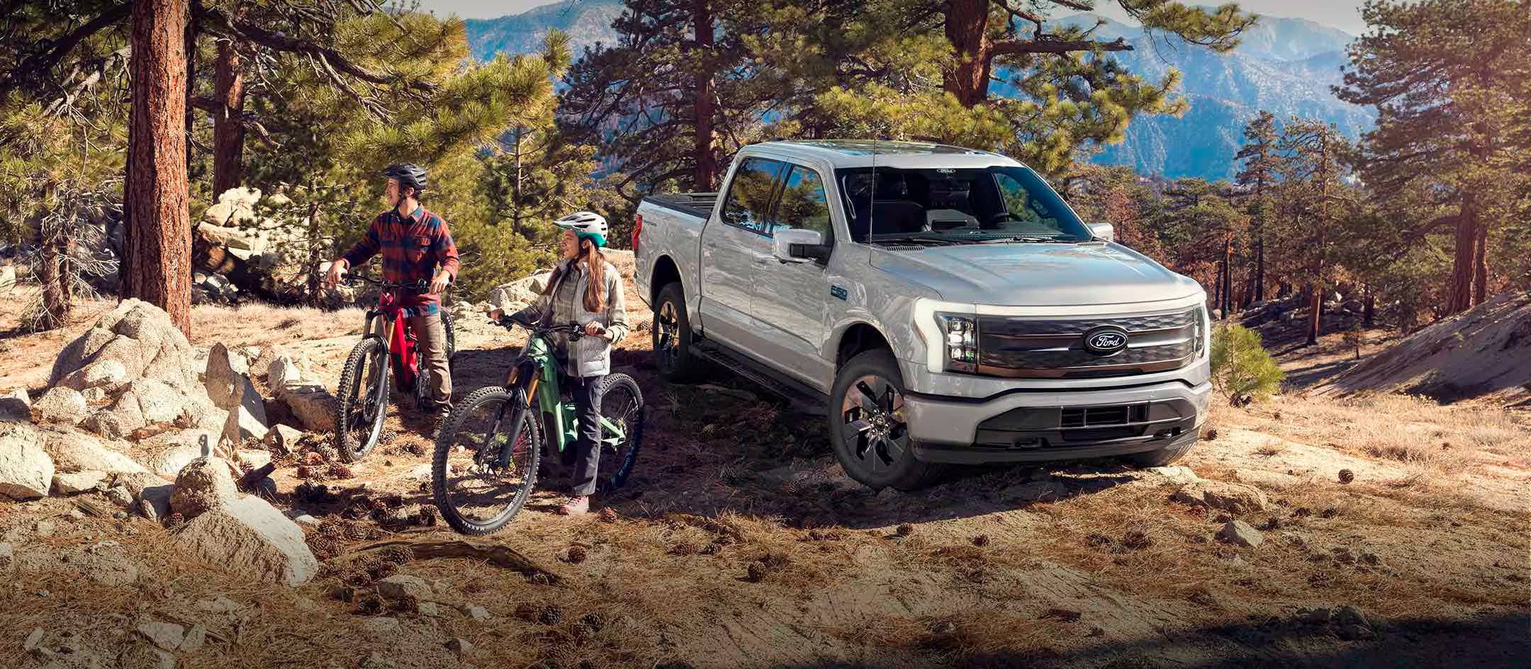 Two people stand with bicycles beside a Ford f 150 Lightning.