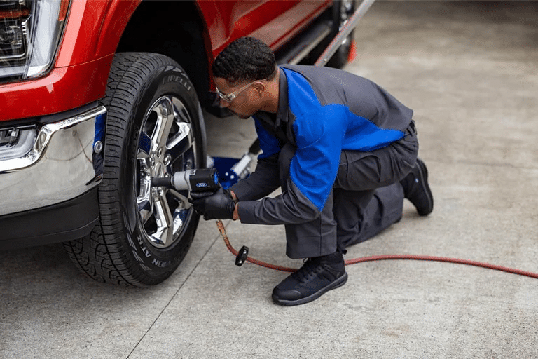 A Ford technician tightens the lugs on a weel. 