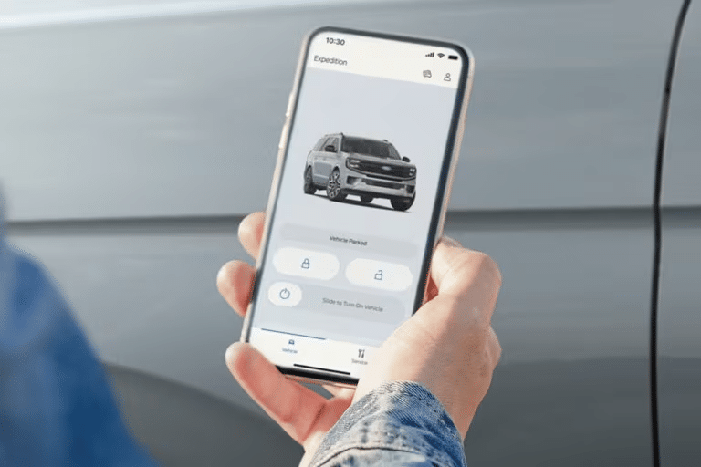 A hand holds a phone with the screen showing the FordPass App. 