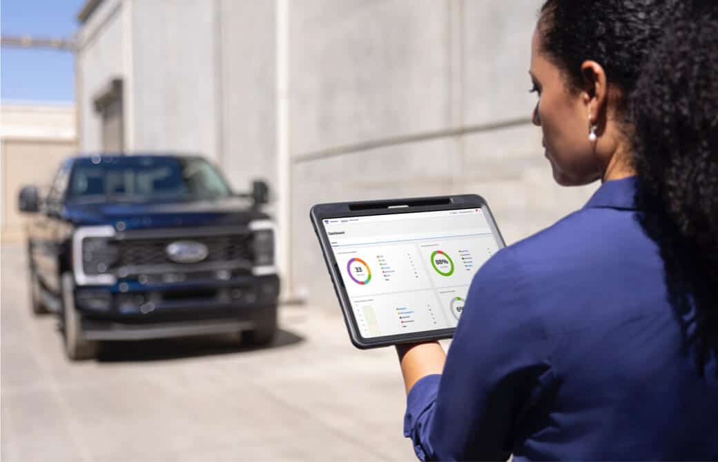 A woman looking at a tablet with a Ford truck in the background