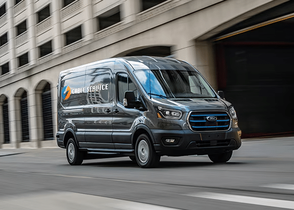 Ford E-Transit Cargo Van driving down a street.