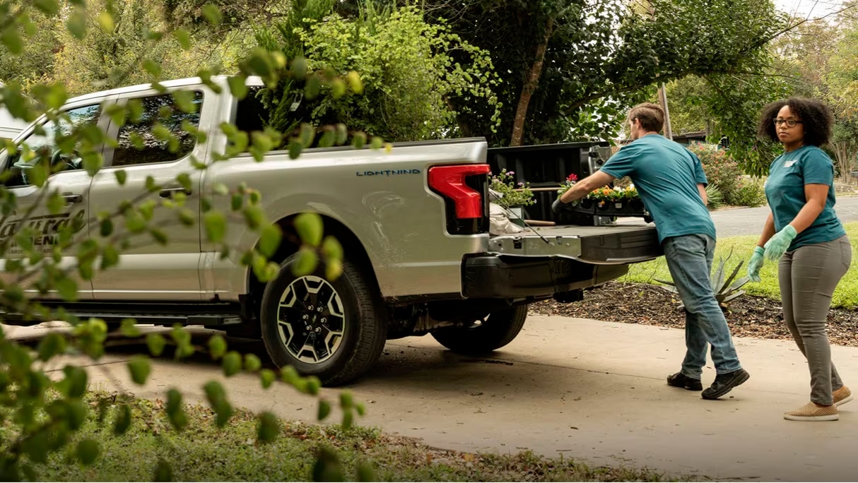 Two landscapers at a project site off-loading plants from the bed of a Ford F150 Lightning truck.