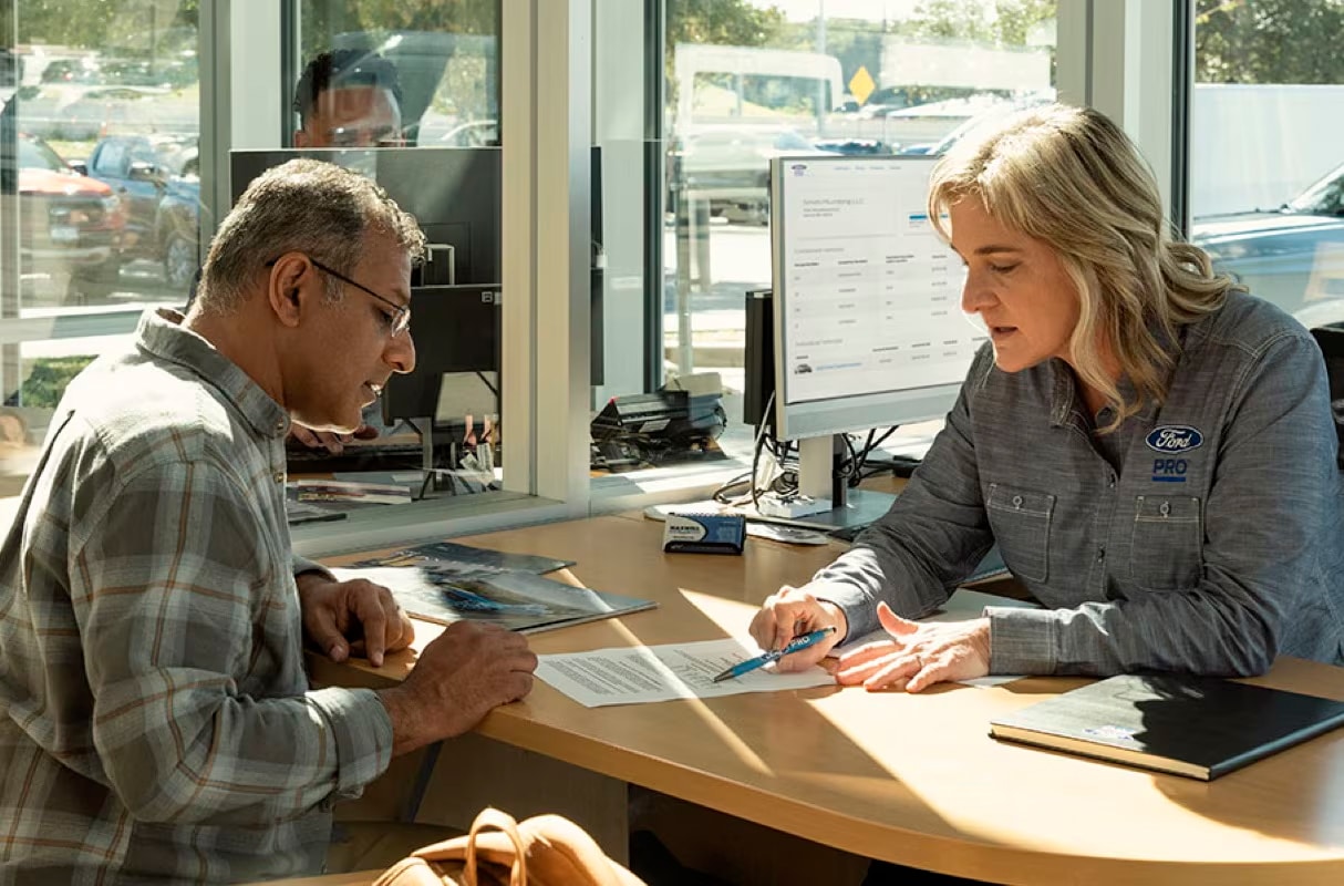 Female business manager reviews finance contract with male fleet manager.