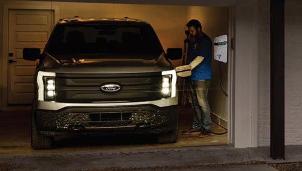 Man plugging in a Ford Lightning into a home charger in a garage