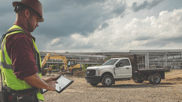 A worker looking at a tablet on a job site.