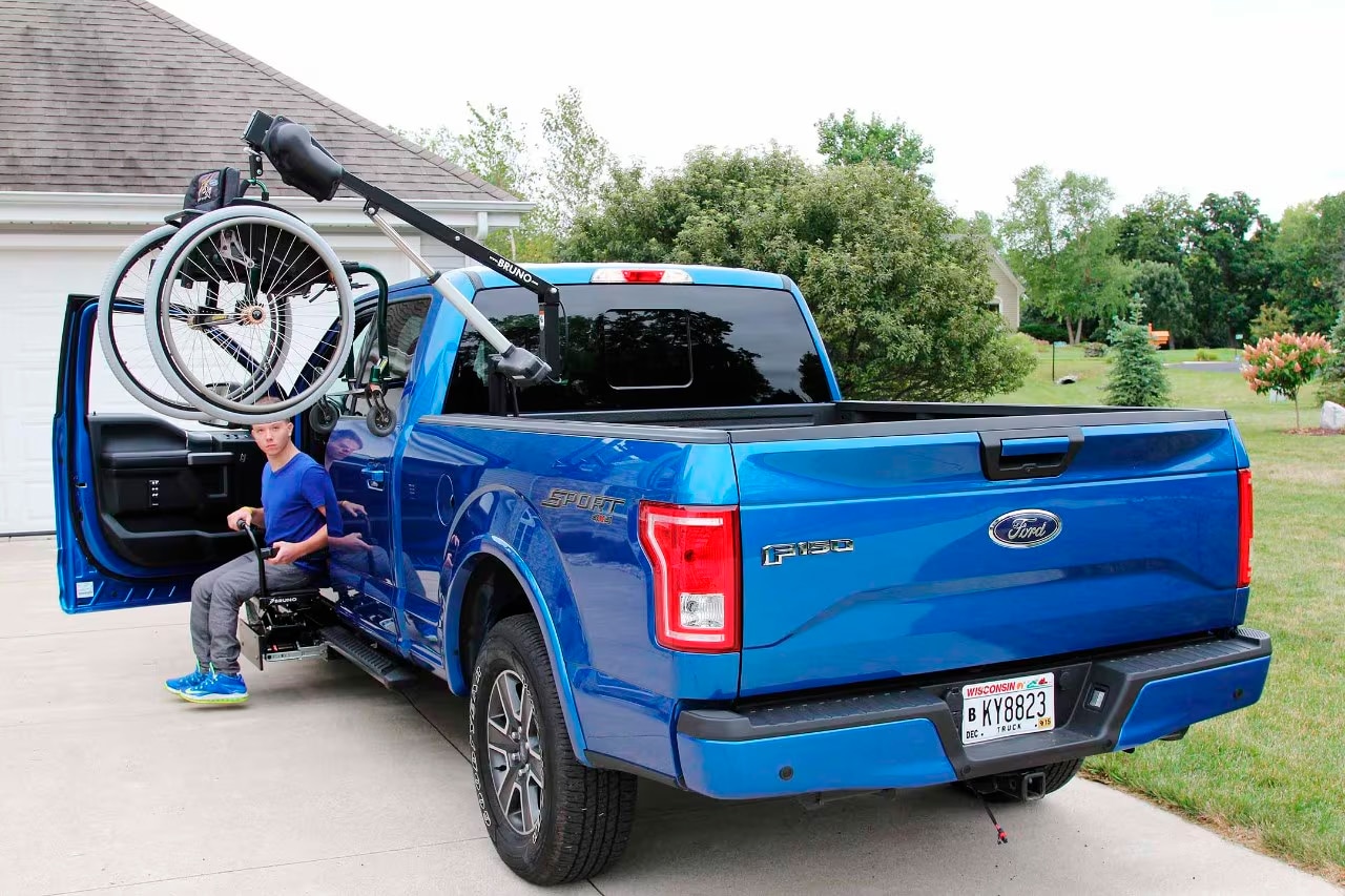 A blue F-150 with a wheelchair hoist in the bed.