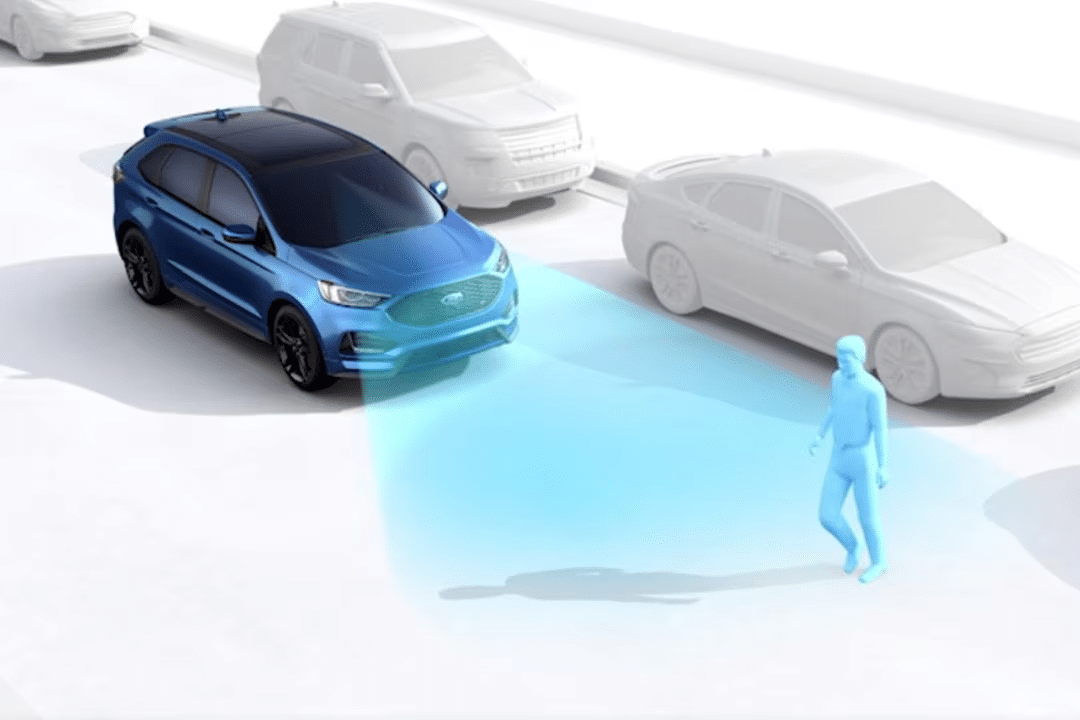 A blue Ford vehicle uses sensors to detect a pedestrian crossing in front of it, illustrated by a blue cone-shaped light projecting from the car. Other cars and the background are shown in gray.