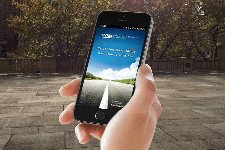 Hand holding mobile phone running the Roadside Assistance app